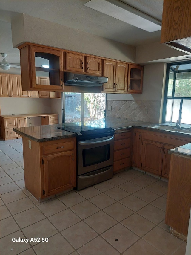 kitchen featuring sink, backsplash, kitchen peninsula, electric range, and light tile patterned floors