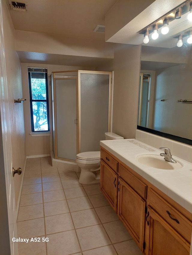 bathroom featuring toilet, tile patterned flooring, a shower with door, and vanity