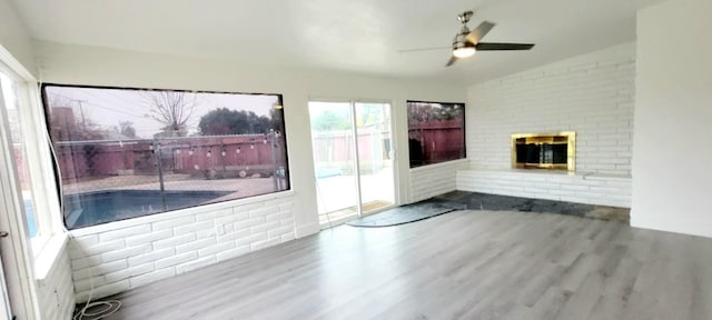 unfurnished living room featuring a brick fireplace, hardwood / wood-style floors, ceiling fan, and vaulted ceiling