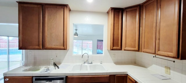 kitchen featuring decorative backsplash, sink, stainless steel dishwasher, and tile countertops