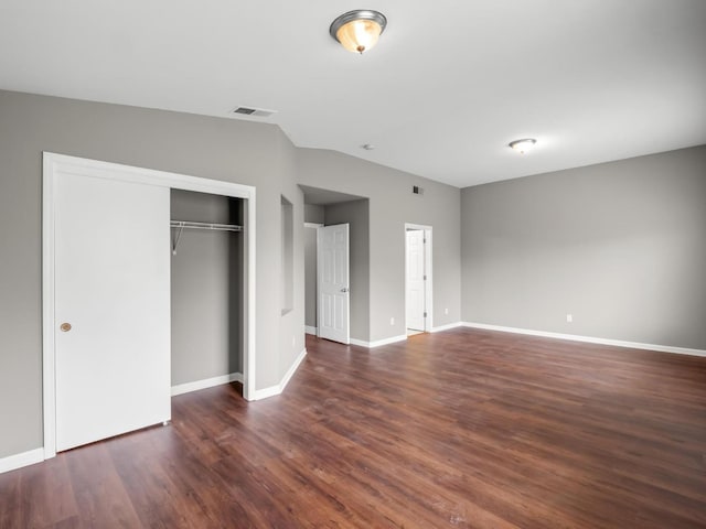 unfurnished bedroom with vaulted ceiling, dark hardwood / wood-style floors, and a closet