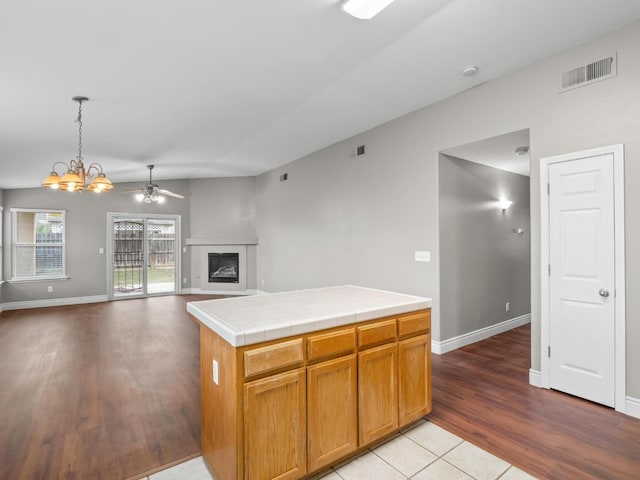 kitchen featuring tile countertops, decorative light fixtures, light hardwood / wood-style floors, ceiling fan with notable chandelier, and a kitchen island