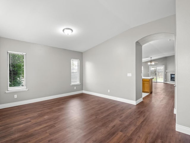 empty room with ceiling fan, lofted ceiling, and dark hardwood / wood-style flooring