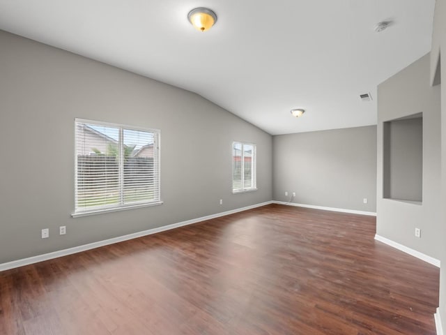 empty room with dark wood-type flooring and lofted ceiling