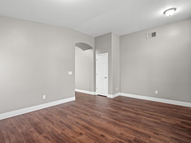 empty room featuring vaulted ceiling and dark hardwood / wood-style floors