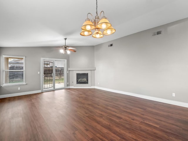 unfurnished living room featuring ceiling fan with notable chandelier, vaulted ceiling, dark hardwood / wood-style floors, and a fireplace