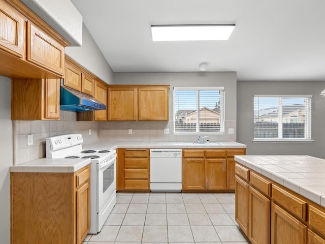 kitchen with tile counters, white appliances, tasteful backsplash, and light tile patterned floors