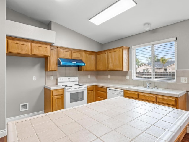 kitchen with tile countertops, white appliances, lofted ceiling, decorative backsplash, and sink