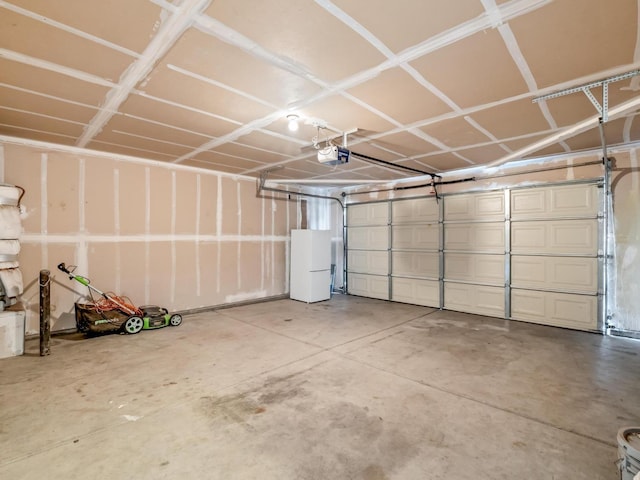 garage featuring white refrigerator and a garage door opener