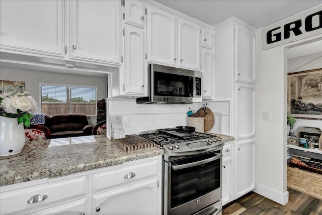 kitchen featuring appliances with stainless steel finishes, dark hardwood / wood-style floors, tasteful backsplash, white cabinets, and light stone counters