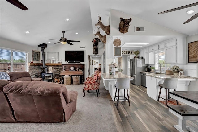 living room with a wood stove, lofted ceiling, and a healthy amount of sunlight