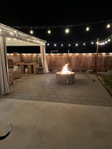 patio at night featuring a fire pit and area for grilling