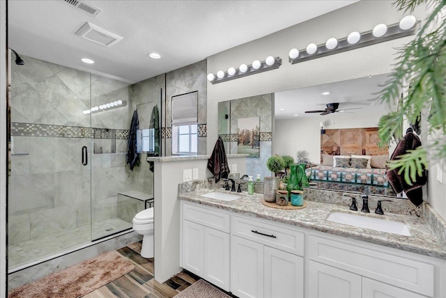 bathroom featuring toilet, ceiling fan, walk in shower, and vanity