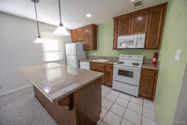 kitchen with a breakfast bar area, white appliances, a sink, visible vents, and hanging light fixtures