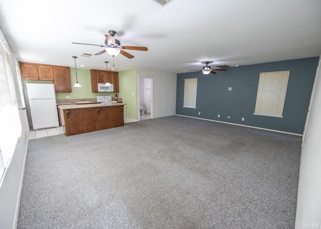 kitchen with white appliances, brown cabinets, open floor plan, light countertops, and pendant lighting