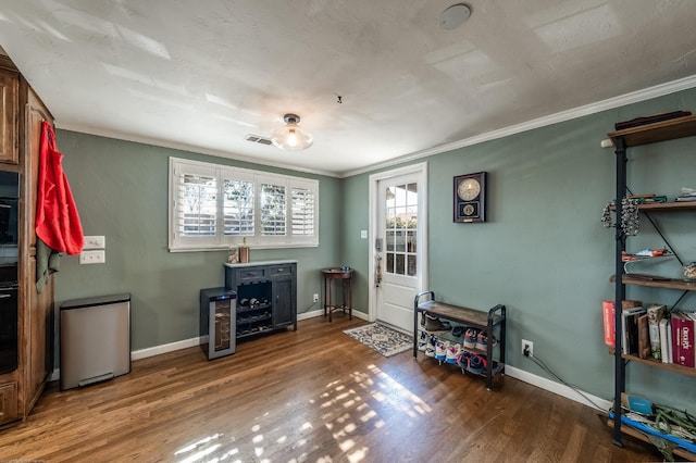 miscellaneous room featuring visible vents, crown molding, baseboards, and wood finished floors