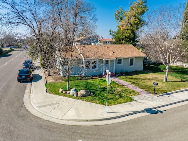 ranch-style home featuring a shingled roof and a front yard