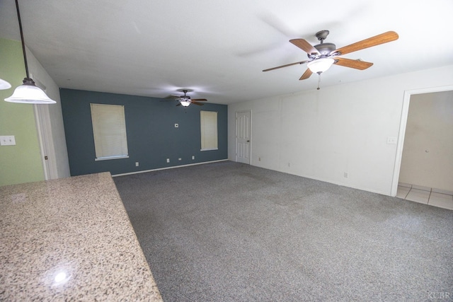 unfurnished room with a ceiling fan and dark colored carpet