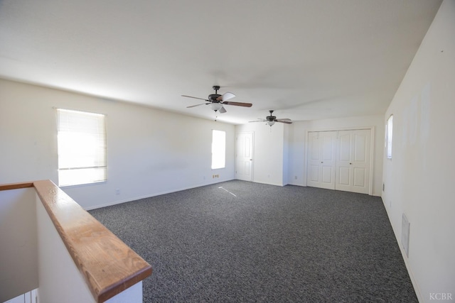 empty room with visible vents, dark carpet, and baseboards