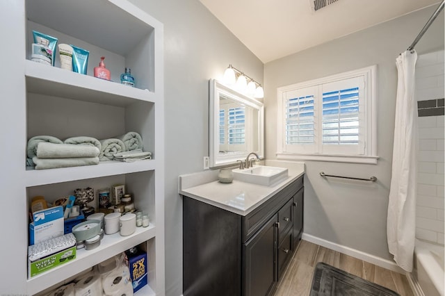 full bathroom featuring baseboards, wood finished floors, vanity, and shower / tub combo with curtain