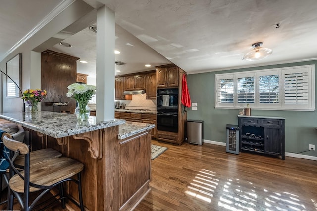 kitchen with a peninsula, stainless steel gas stovetop, a breakfast bar, and crown molding