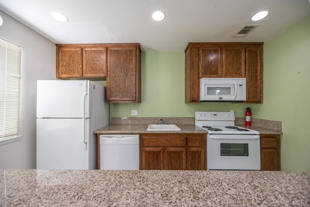 kitchen featuring white appliances, visible vents, brown cabinets, a sink, and recessed lighting