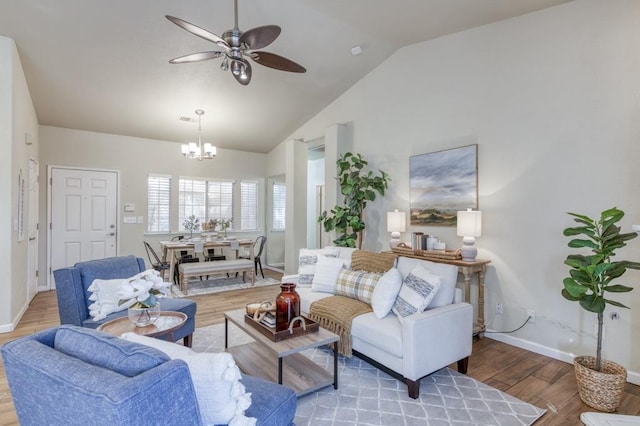 living room with vaulted ceiling, ceiling fan with notable chandelier, and hardwood / wood-style flooring