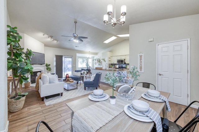 dining space with vaulted ceiling, ceiling fan with notable chandelier, and sink