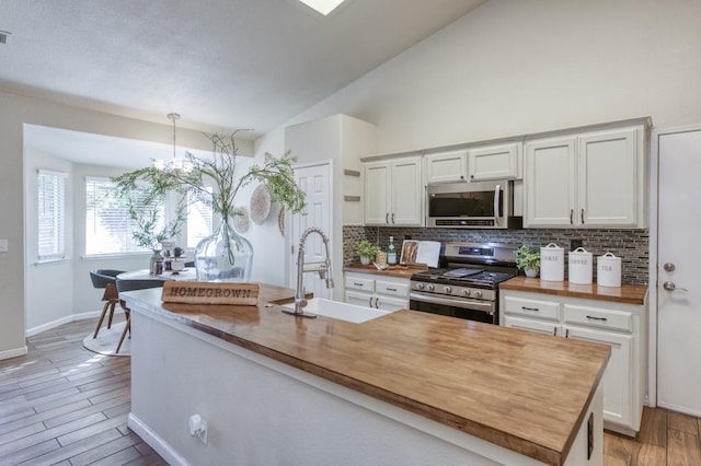 kitchen with pendant lighting, white cabinets, butcher block counters, and stainless steel appliances