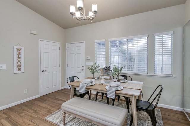 dining area featuring lofted ceiling, wood-type flooring, and a notable chandelier