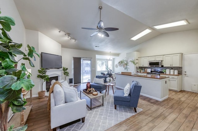 living room featuring vaulted ceiling, ceiling fan, and light hardwood / wood-style flooring