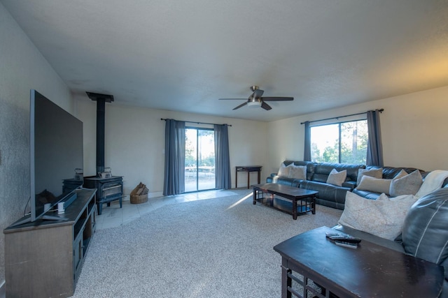 carpeted living room featuring ceiling fan and a wood stove