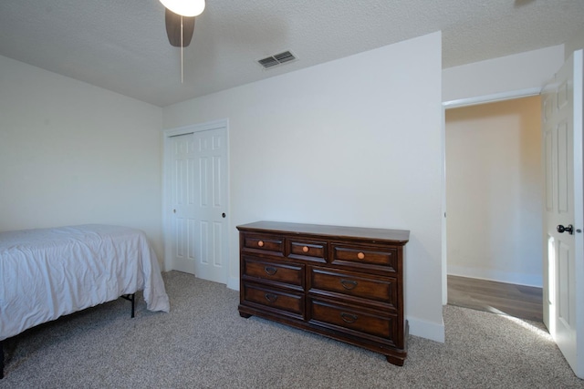 carpeted bedroom featuring ceiling fan, a closet, and a textured ceiling