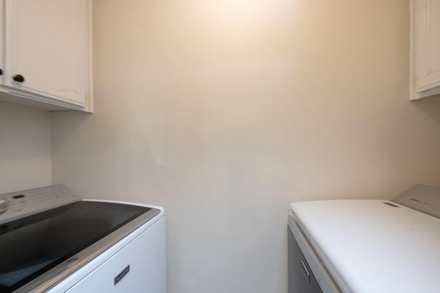 clothes washing area featuring cabinets and separate washer and dryer