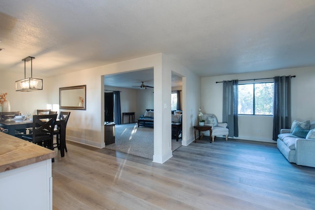 living room with light hardwood / wood-style floors, a textured ceiling, and ceiling fan