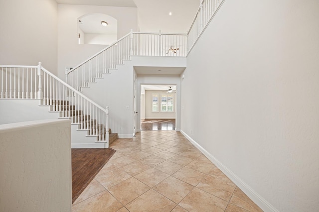 tiled foyer featuring ceiling fan and a towering ceiling