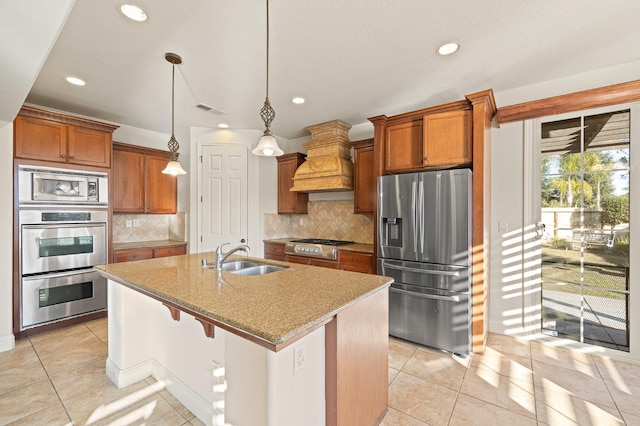 kitchen with decorative light fixtures, backsplash, premium range hood, sink, and appliances with stainless steel finishes