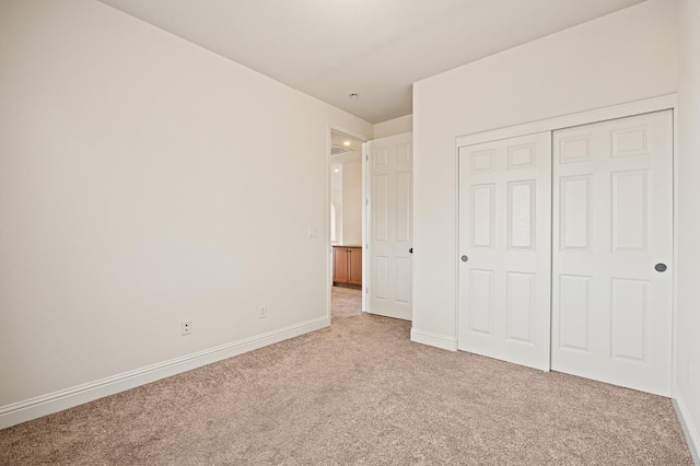 unfurnished bedroom featuring light colored carpet and a closet