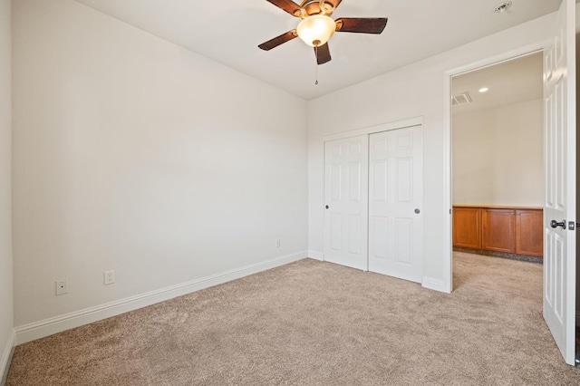 unfurnished bedroom featuring light carpet, ceiling fan, and a closet