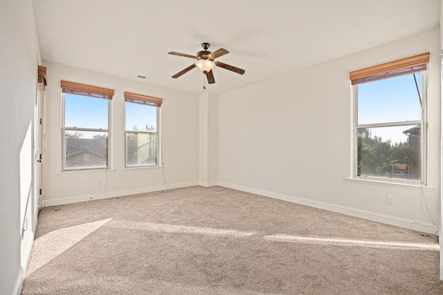 spare room featuring ceiling fan, light colored carpet, and plenty of natural light