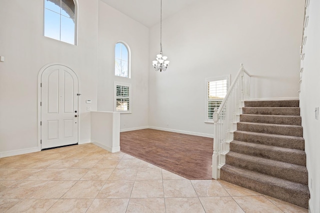 tiled foyer featuring a towering ceiling, plenty of natural light, and a chandelier