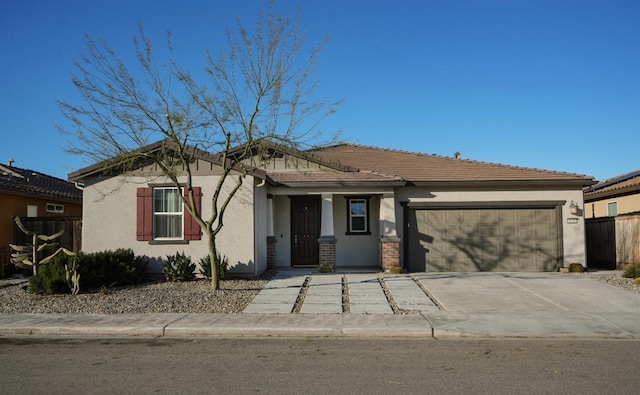 view of front of home featuring fence, a garage, driveway, and stucco siding