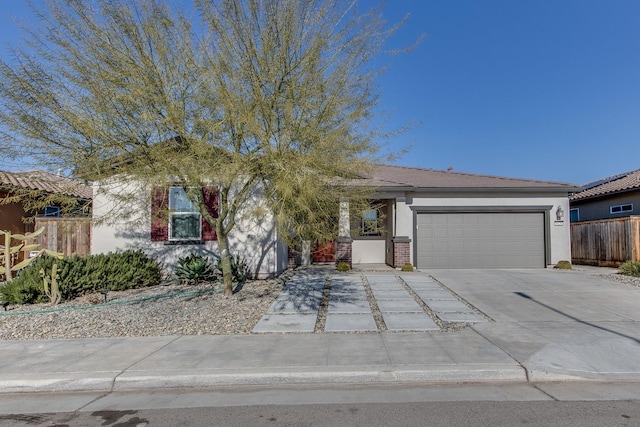 view of front of property featuring brick siding, fence, stucco siding, driveway, and an attached garage