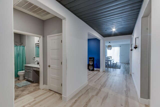 hallway featuring light hardwood / wood-style floors, sink, and an inviting chandelier