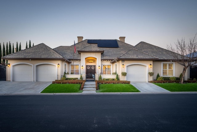 view of front of property featuring a lawn, solar panels, and a garage