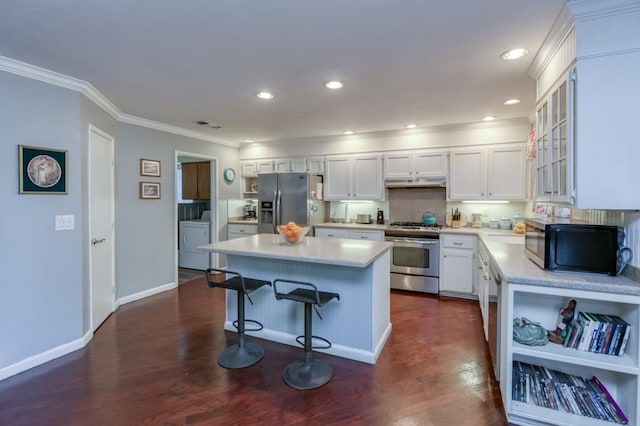 kitchen with white cabinets, a center island, stainless steel appliances, dark hardwood / wood-style floors, and independent washer and dryer