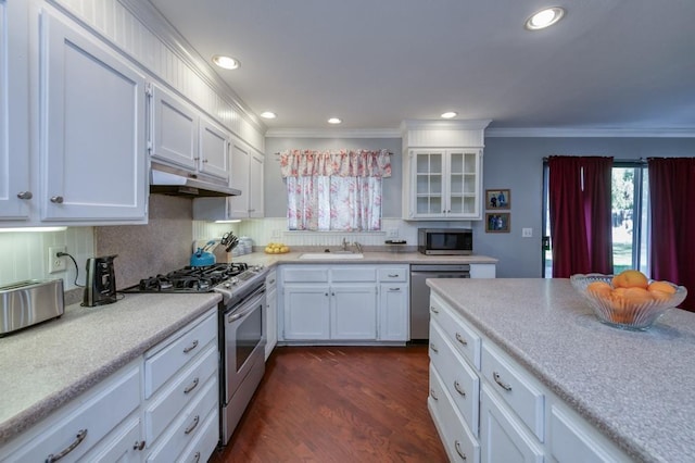 kitchen with white cabinets, appliances with stainless steel finishes, dark wood-type flooring, sink, and crown molding