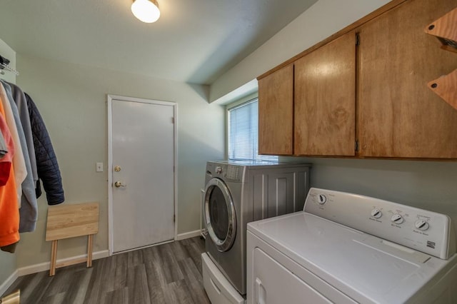 clothes washing area featuring dark wood-type flooring, cabinets, and washing machine and dryer