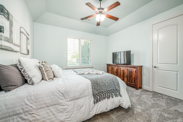 carpeted bedroom with ceiling fan, a tray ceiling, and vaulted ceiling