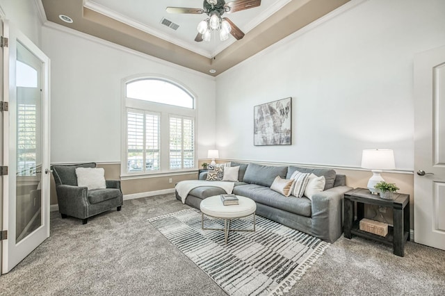 carpeted living room with ceiling fan, crown molding, and a tray ceiling